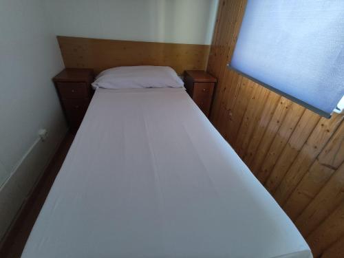 a white bed in a small room with a window at Camping Cases in Les Cases d'Alcanar