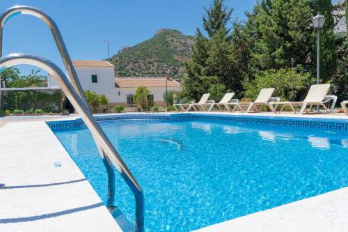 a swimming pool with lounge chairs and a resort at Alojamiento Rural el Viso in El Chorro