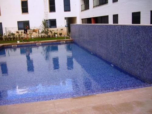 una piscina blu con recinzione di fronte a un edificio di Apartamento Cala Busquets a Ciutadella