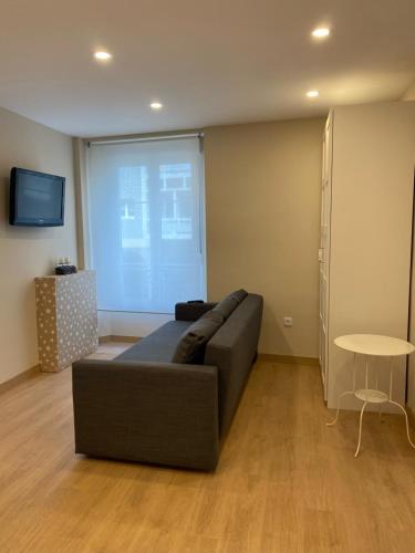 a living room with a couch and a large window at Alojamientos Muelle de Gijón in Gijón