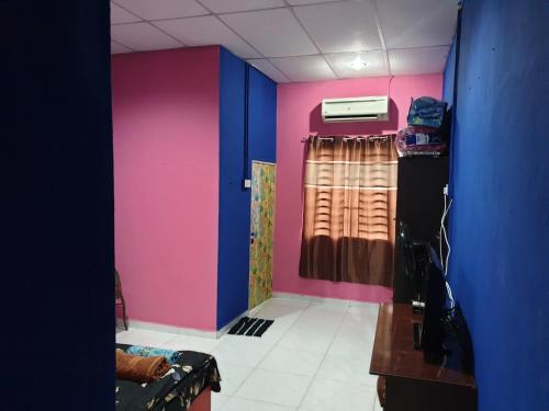 Cette chambre présente des murs roses et bleus. dans l'établissement InapDesa Studio Kangar Perlis, à Kangar