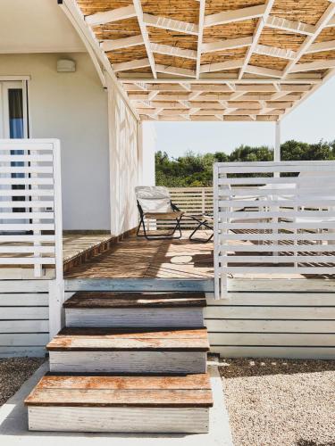 a porch with a white pergola and a chair at Macchia Piccinna in Maruggio