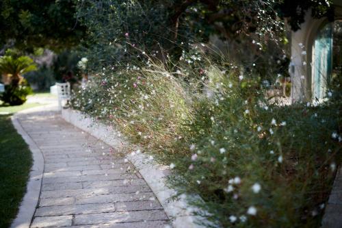 a garden with flowers and a brick sidewalk at Montiro' Hotel in Leuca