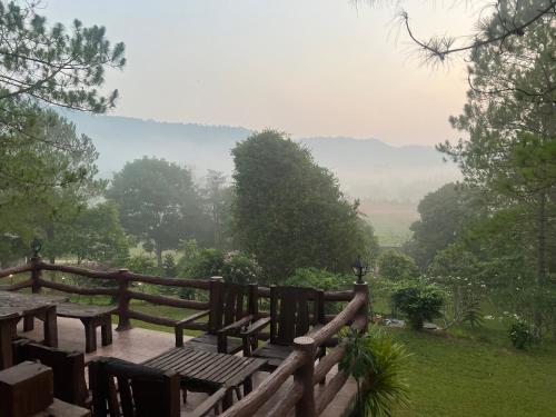 a wooden deck with a picnic table and a view at ไร่นุชชม รีสอร์ทเขาค้อ in Ban Non Na Yao