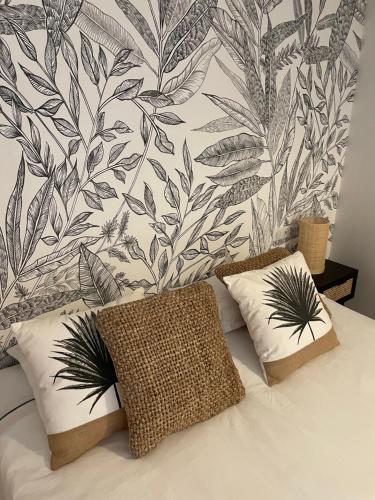 a bed with two pillows and a wall with leaves at Hôtel Restaurant La Caravelle in Sari Solenzara