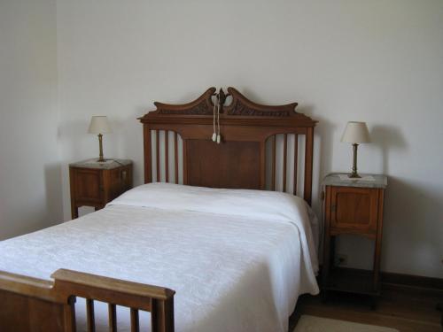 een slaapkamer met een houten bed en 2 nachtkastjes bij Vila Guiomar - Casa da Eira in Alvarenga