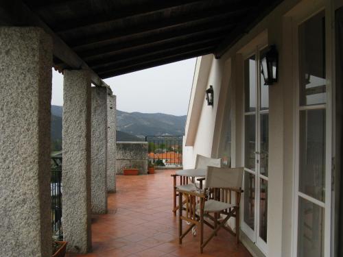 Un patio con sillas y una mesa en el balcón. en Vila Guiomar - Casa da Eira en Alvarenga