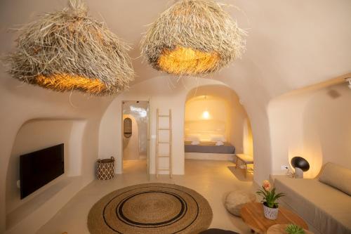 una sala de estar con 2 lámparas de araña colgando del techo en La Casa de Caldera, en Oia