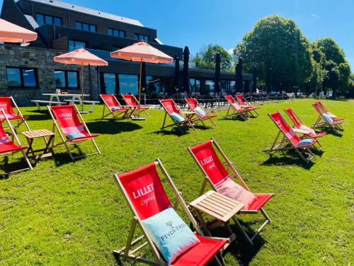 a bunch of red chairs and umbrellas in the grass at Le Mont Rigi in Waimes