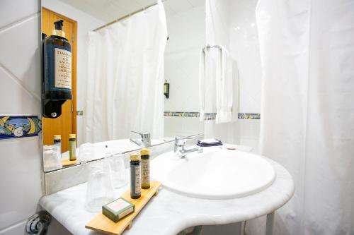 a white bathroom with a sink and a mirror at Hotel do Mar in Povoação