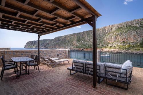 a patio with a table and chairs and a view of the ocean at Guesthouse Laoula in Gerolimenas