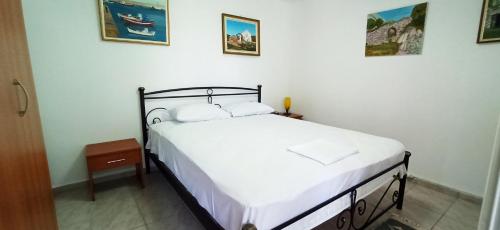 um quarto com uma cama com lençóis brancos e fotografias na parede em Maris full apartment with roof garden access em Quios