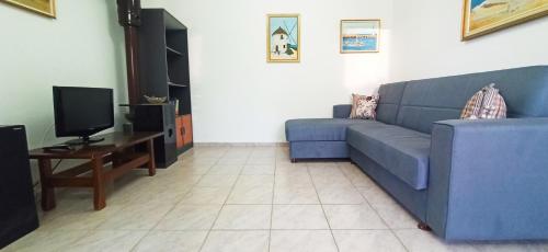 a living room with a blue couch and a tv at Maris full apartment with roof garden access in Chios