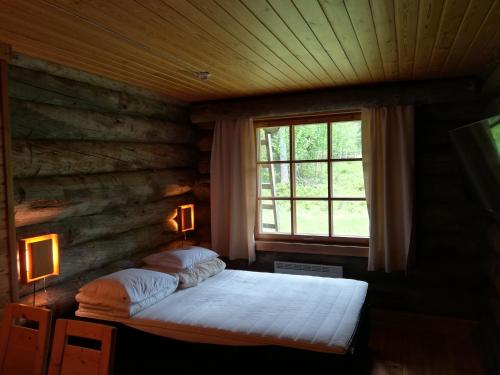 una camera con un letto in una baita di tronchi di Kelo Seasons Spring a Luosto
