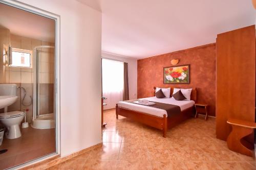 a bedroom with a bed and a bathroom with a mirror at VILA HAVEN - Camere de inchiriat in Costinesti