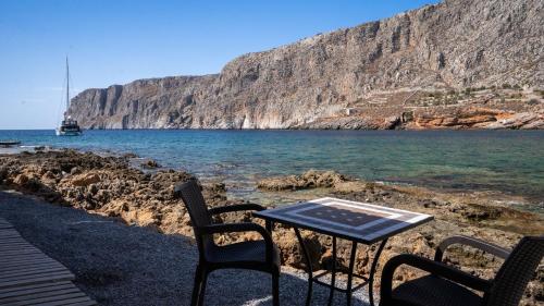 a table and chairs sitting next to the water at Guesthouse Laoula in Gerolimenas