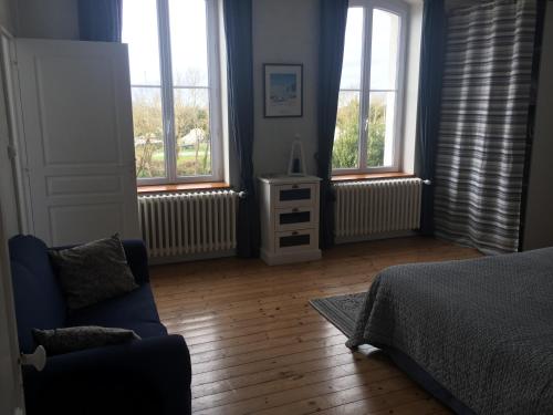 a bedroom with windows and a bed and a couch at Le Logis du Canal in Marennes