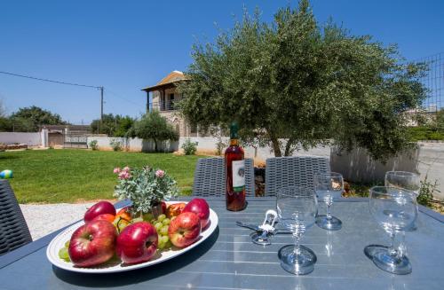 a plate of fruit on a table with a bottle of wine at Casa Magnolia in Kathiana