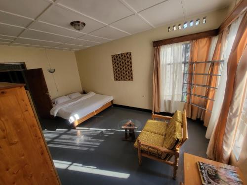 um quarto com uma cama, uma cadeira e uma mesa em Maddy's Kitchen and Accomodation em Gisenyi