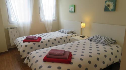 two twin beds in a room with a lamp at Apartamentos Somo 2 in Somo