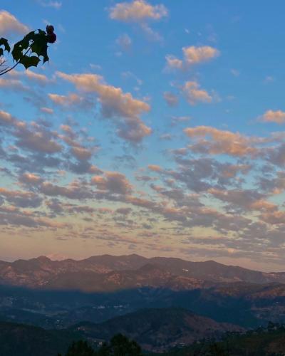 a person is flying a kite in the sky at Shantiniketan Mountain Home in Almora