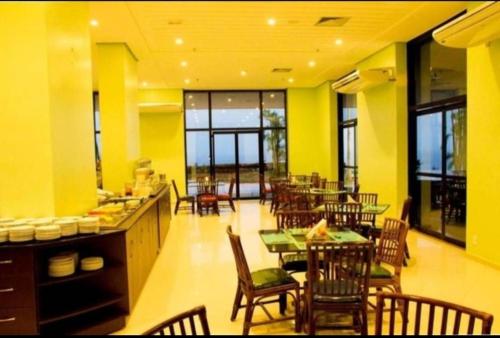 a dining room with tables and chairs and yellow walls at Tropical Executive Vista pra Praia in Manaus