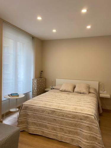 a bedroom with a large bed and a table at Alojamientos Muelle de Gijón in Gijón