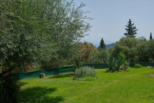 a garden with a green fence and some trees at Villa Boukari in Chlomós