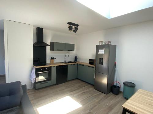 eine Küche mit einem Kühlschrank aus Edelstahl und einem Tisch in der Unterkunft Maison vacance in Sainte-Soulle