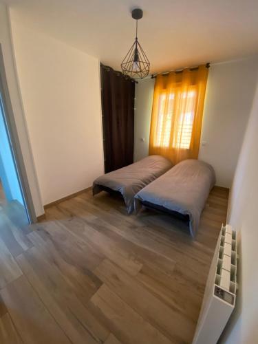 2 Betten in einem Zimmer mit Holzböden und einem Fenster in der Unterkunft Maison vacance in Sainte-Soulle