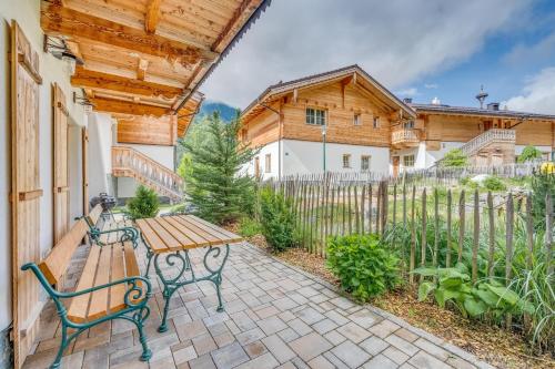 a patio with a wooden table and a bench at Chaletdorf am Sonnenhang in Neukirchen am Großvenediger