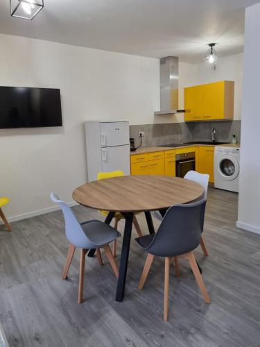 une table et des chaises dans une cuisine avec des armoires jaunes dans l'établissement Coeur de Cauterets appartement 53m² 4/6 personnes, à Cauterets