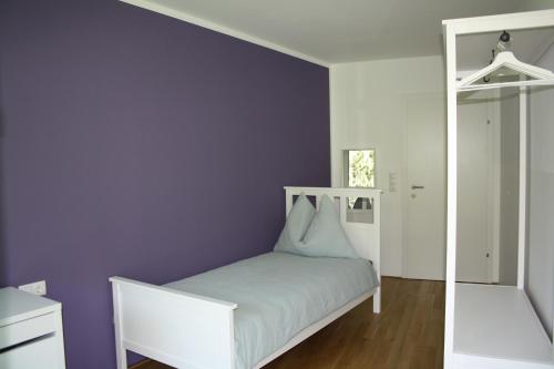 ein Schlafzimmer mit einem weißen Bett und einer lila Wand in der Unterkunft Felseck Zimmer in Innsbruck