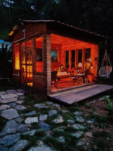a small wooden cabin with a deck and a table at Shantiniketan Mountain Home in Almora