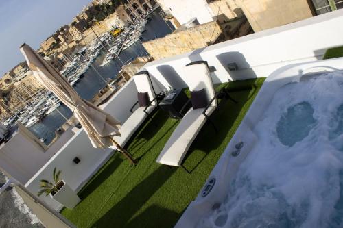 a balcony with chairs and a pool on a building at BEBIRGU PALAZZINO LUXURY 2 jacuzzi to share in Vittoriosa