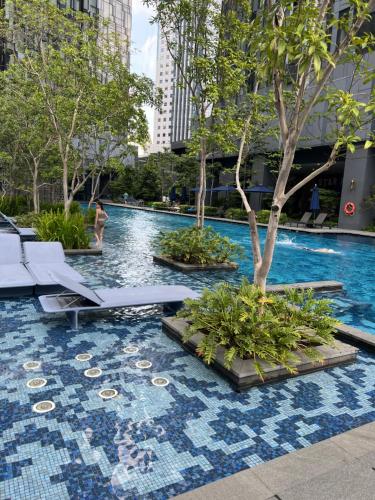 吉隆坡的住宿－Star Residence KLCC By FZB，城市里一座带椅子和树的游泳池