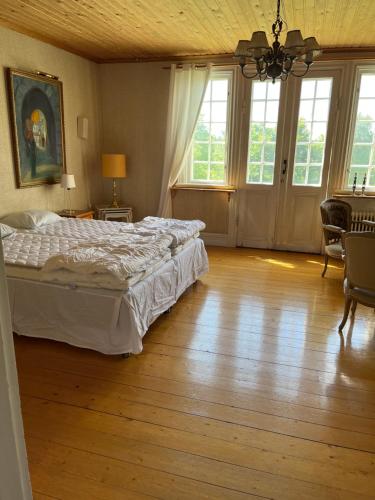 een slaapkamer met een bed en houten vloeren en ramen bij Trunna Vandrarhem & Konferens in Orsa