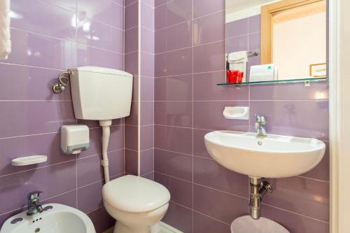 a purple bathroom with a toilet and a sink at Hotel Milanese in Rimini