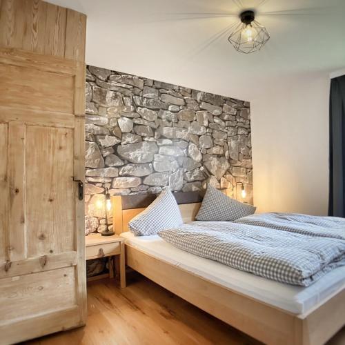 a bedroom with a stone wall and a bed at Gasthof Auwirt in Sankt Michael im Lungau