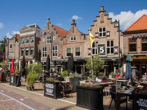 a group of buildings on a street with tables at Bij het meertje! in Dirkshorn