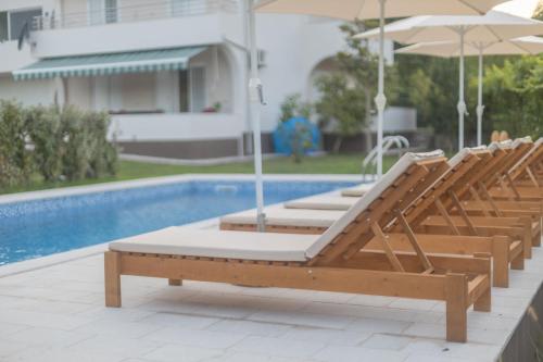 un grupo de tumbonas con sombrillas junto a la piscina en Villa MontAnja, en Herceg-Novi