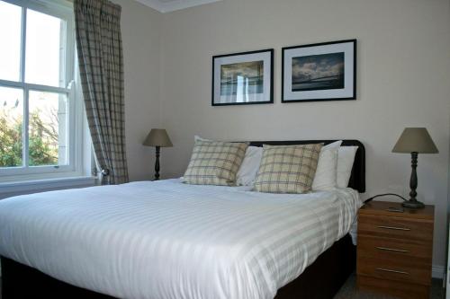 a bedroom with a white bed with two lamps and a window at Loch Ness Guest House in Fort Augustus