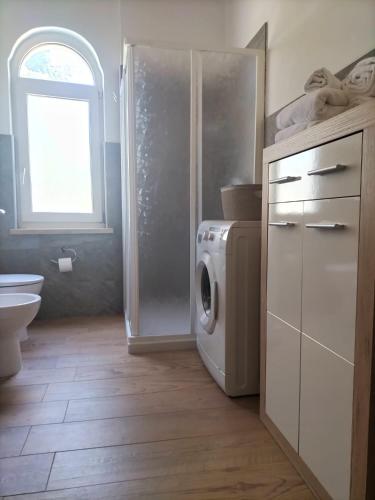 een badkamer met een wasmachine en droger naast een raam bij Apartment Dea in Cles