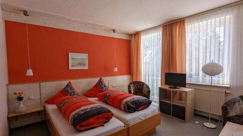 Schlafzimmer mit orangefarbenen Wänden und einem Bett mit Kissen in der Unterkunft Hotel Heilbrunnen in Jöhstadt