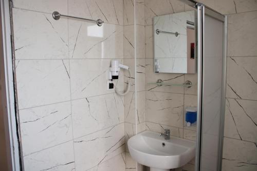 a white bathroom with a sink and a shower at Max Nova Hotel in Alanya