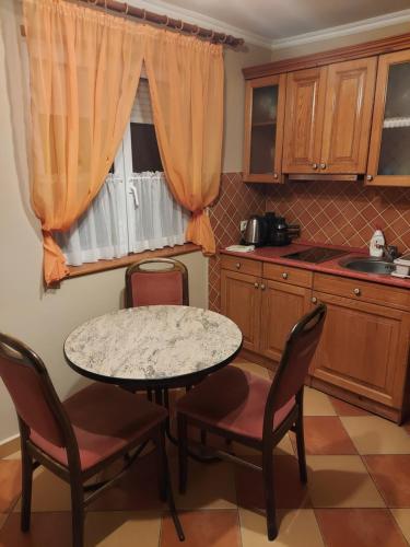 a kitchen with a table and chairs and a window at Mediterrán Vendégház in Nagyatád