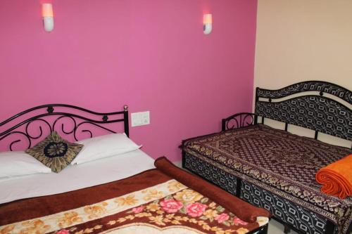 two beds in a room with purple walls at Hirai Palace, Mahabaleshwar in Mahabaleshwar