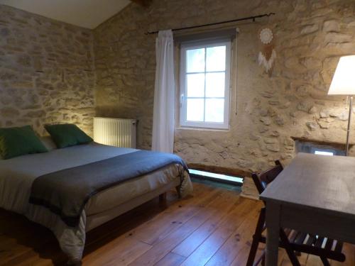 a bedroom with a bed and a window and a table at Malia - Chambres d'hôtes & Gîte in Barret-de-Lioure