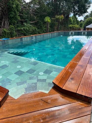 a swimming pool with a wooden deck and blue water at La tanière de Bonneville in Bonneville-sur-Touques