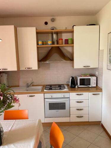 a kitchen with white cabinets and a microwave at RESORT VILLAGE AQUA MARINA FAMILY - Daily Rooms Tidying - CocktailsBar- Pet Friendly - with Hypermarket - Delivery Restaurant-Pizzeria - Room Breakfast with supplement - Ultra Fast Wi-Fi - Play Area for children - Olympic Swimming Pool - Parking in Caorle